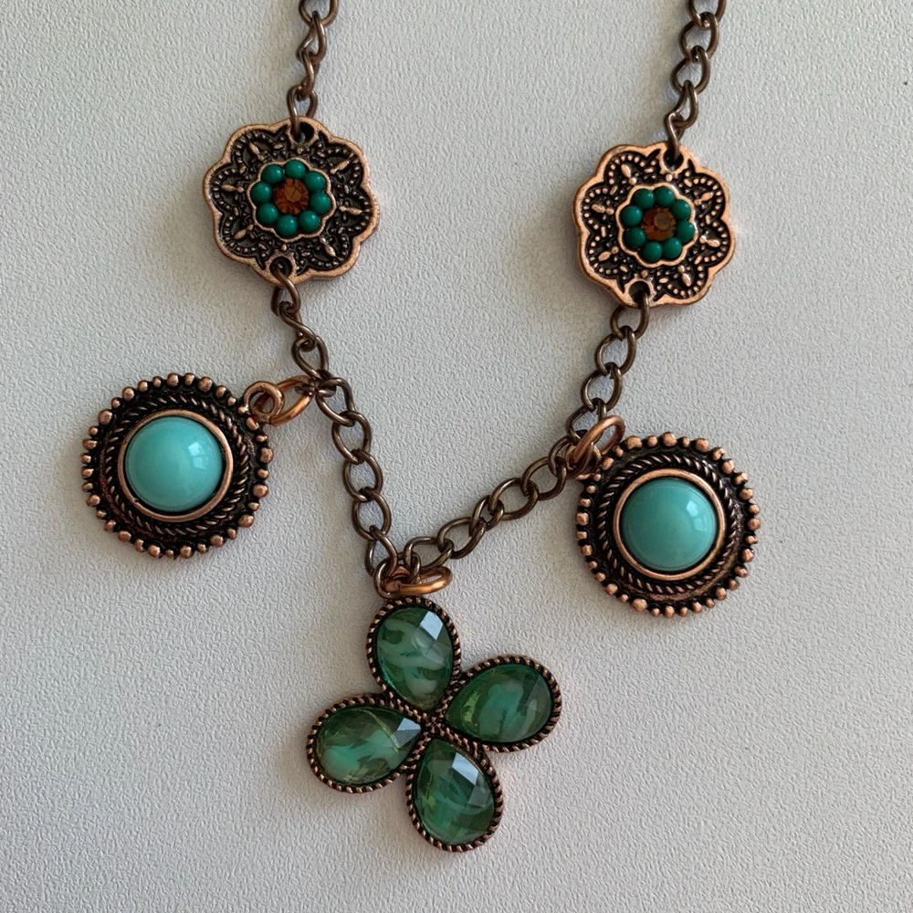 Unique copper tone dangle necklace with unique charms in shades of turquoise.